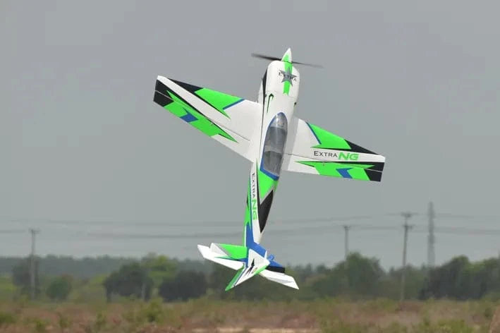 Sleek green and white RC plane, Phoenix Model Extra Next Gen 50cc Carbon ARF, soaring over grassy field.