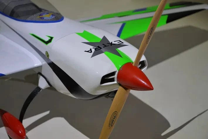 Sleek green and white RC plane with carbon fiber components and a red propeller.