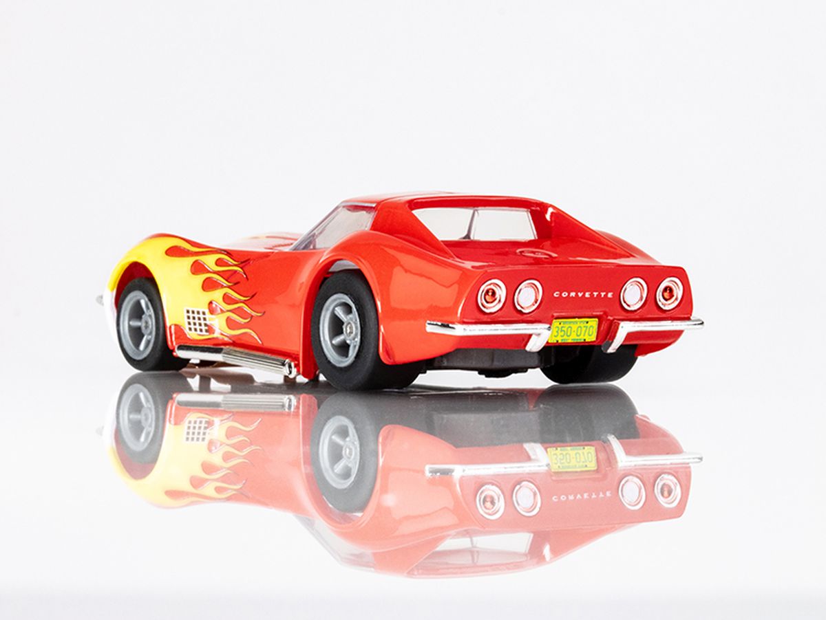 Vibrant red and yellow flame Corvette slot car on a reflective surface.