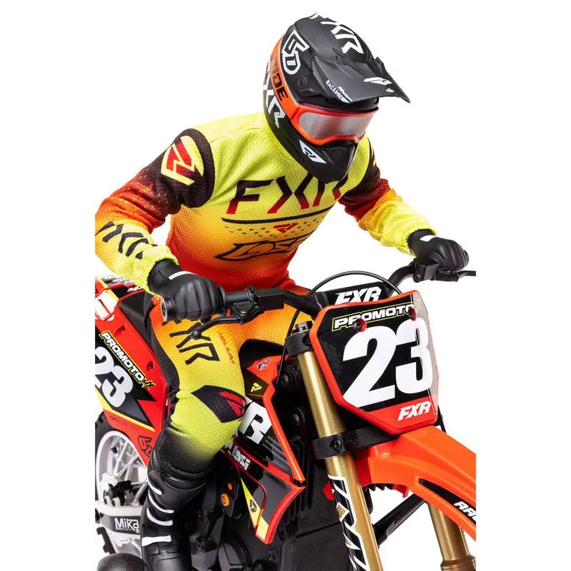 Stylized RC motorcycle with FXR branding and number 23, ridden by a driver wearing a protective helmet and bright yellow and orange racing gear.
