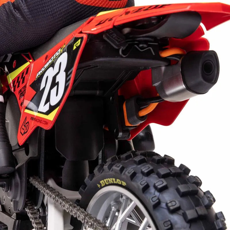 Detailed red and black RC motorcycle model with racing number 23, large exhaust, and rugged off-road tires.