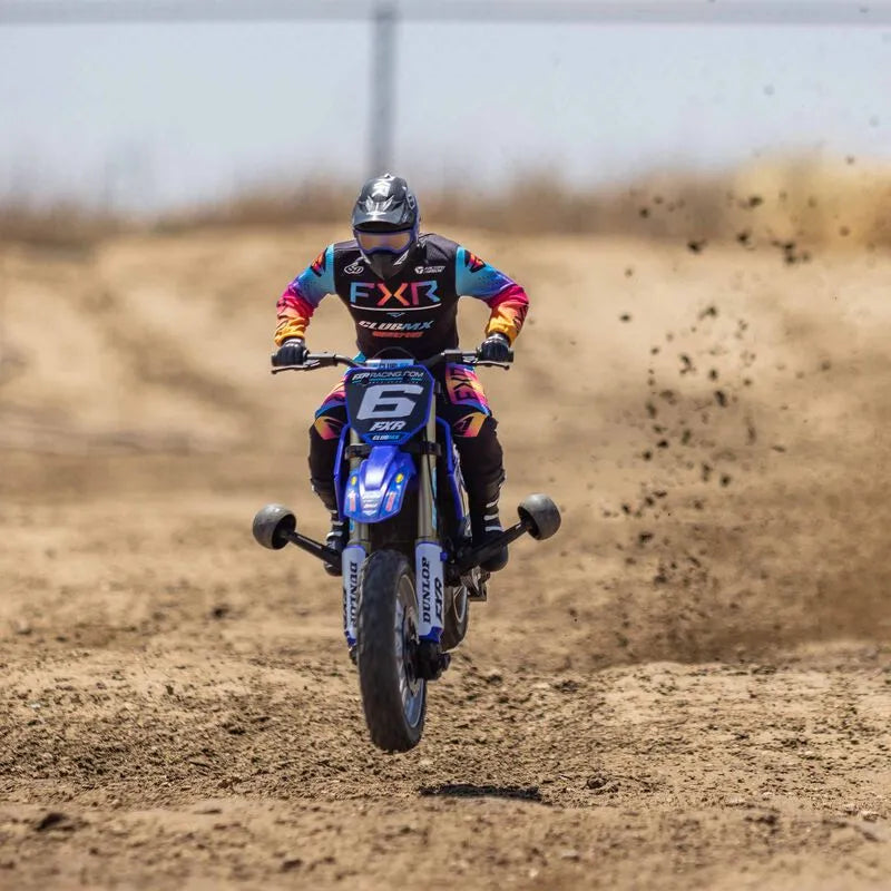 Colorful off-road motorcycle in action, kicking up dirt on a dusty track.