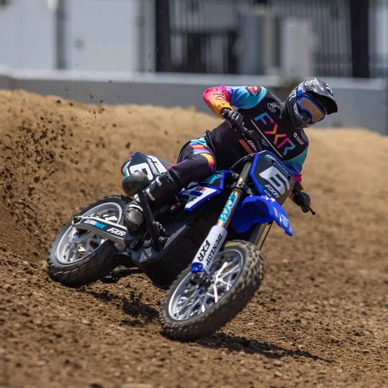Detailed 1/4 scale radio-controlled dirt bike in vibrant blue, red and yellow color scheme racing on a dirt track