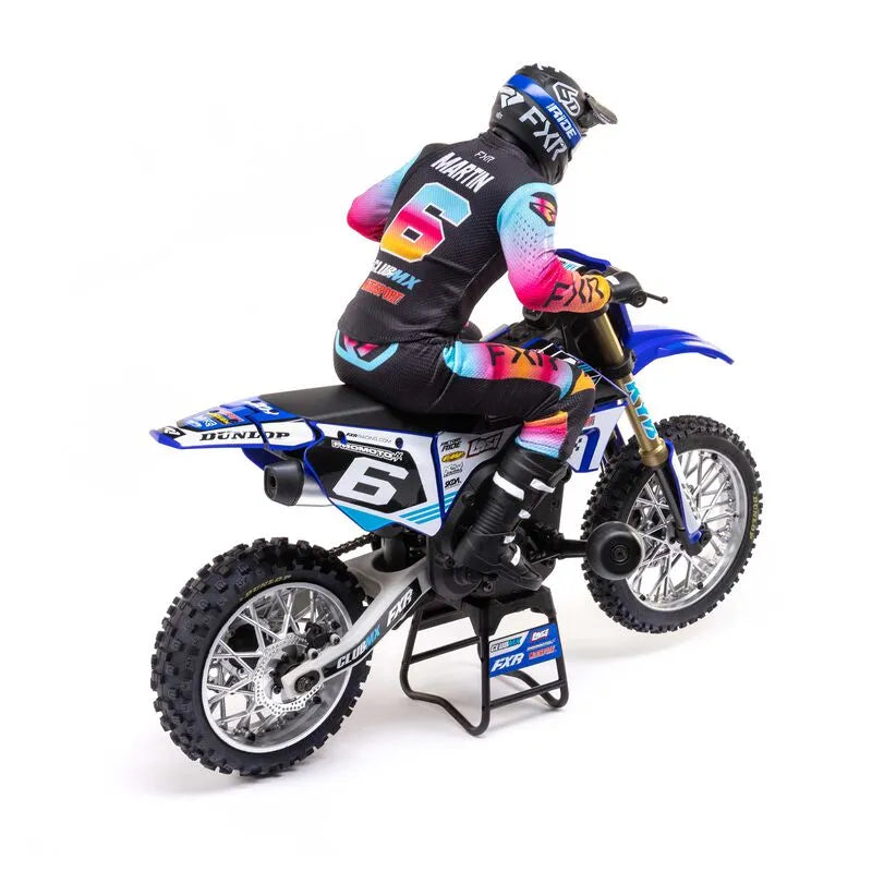 Detailed, vibrant RC motorcycle on dirt track with driver in colorful racing gear.