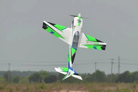 Sleek green and white RC plane, Phoenix Model Extra Next Gen 50cc Carbon ARF, soaring over grassy field.